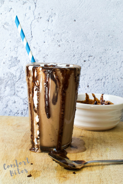 dairy free chocolate milkshake with carob sauce and blue and white striped straw