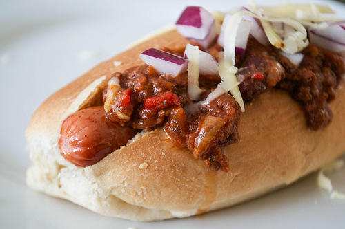 chilli dog with red onion and cheddar cheese